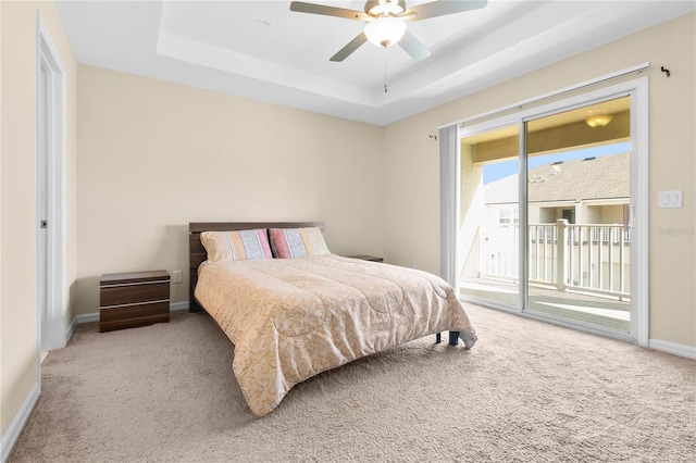 carpeted bedroom with a tray ceiling, access to exterior, and ceiling fan