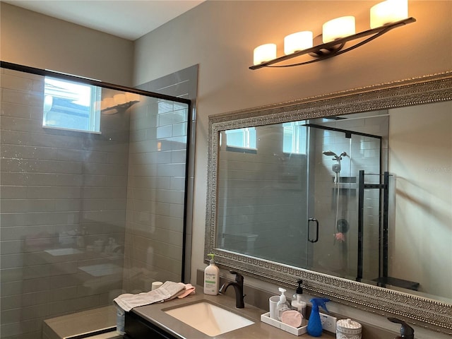 bathroom featuring vanity, a healthy amount of sunlight, and a shower with door