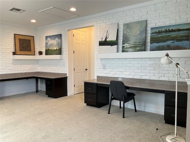 carpeted office space featuring built in desk and brick wall