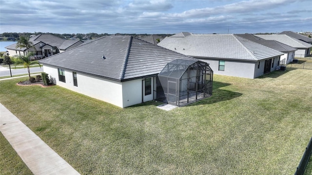 back of property with central AC, glass enclosure, and a lawn