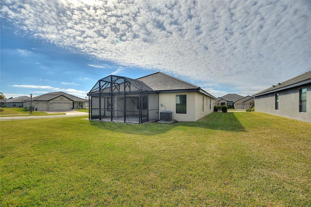 back of property with central AC unit, a lanai, and a lawn