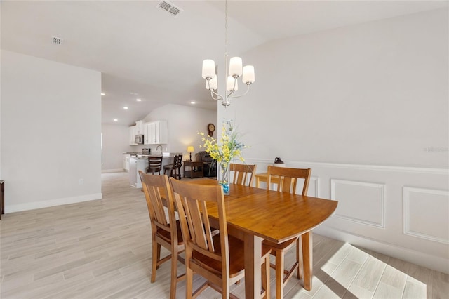 dining room featuring light hardwood / wood-style flooring, lofted ceiling, and a notable chandelier