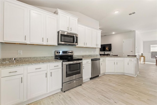 kitchen with white cabinetry, light wood-type flooring, kitchen peninsula, and stainless steel appliances