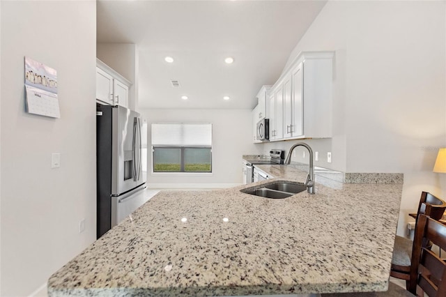 kitchen featuring white cabinets, light stone counters, kitchen peninsula, and appliances with stainless steel finishes