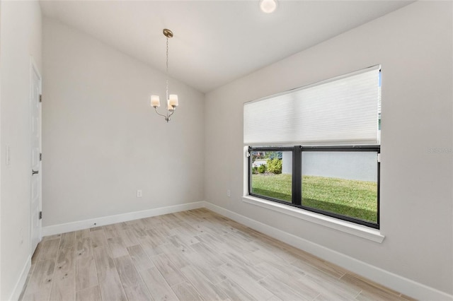 empty room featuring an inviting chandelier, light hardwood / wood-style flooring, and vaulted ceiling