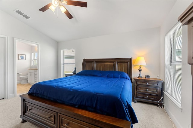 bedroom featuring light carpet, vaulted ceiling, ensuite bath, and ceiling fan