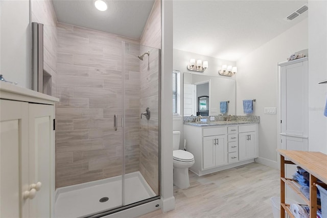 bathroom featuring vanity, a shower with shower door, and toilet