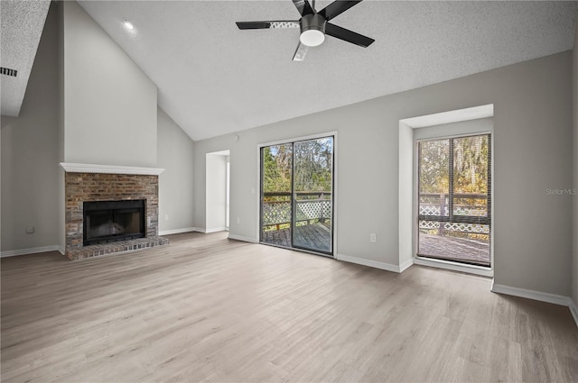 unfurnished living room with ceiling fan, a fireplace, light hardwood / wood-style floors, and a textured ceiling