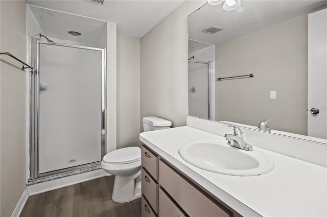 bathroom with hardwood / wood-style floors, vanity, toilet, and a shower with shower door