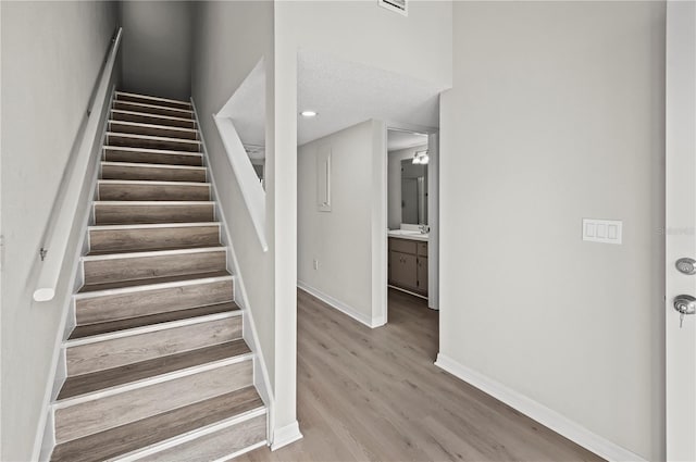 staircase featuring hardwood / wood-style floors, sink, and a textured ceiling