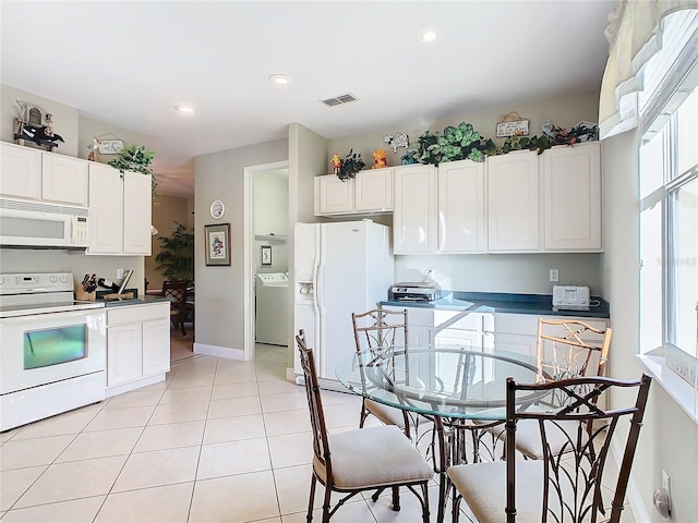 kitchen with light tile patterned floors, white cabinets, washer / clothes dryer, and white appliances