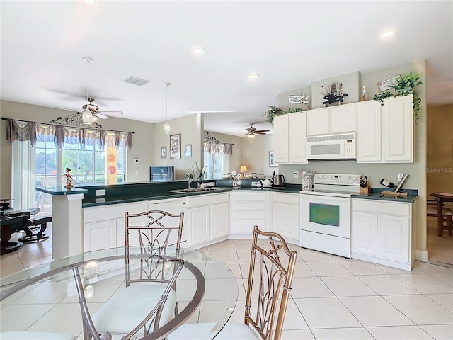 kitchen featuring a wealth of natural light, white appliances, kitchen peninsula, and light tile patterned flooring