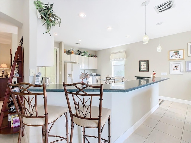 kitchen featuring a kitchen bar, kitchen peninsula, white cabinetry, hanging light fixtures, and white fridge with ice dispenser