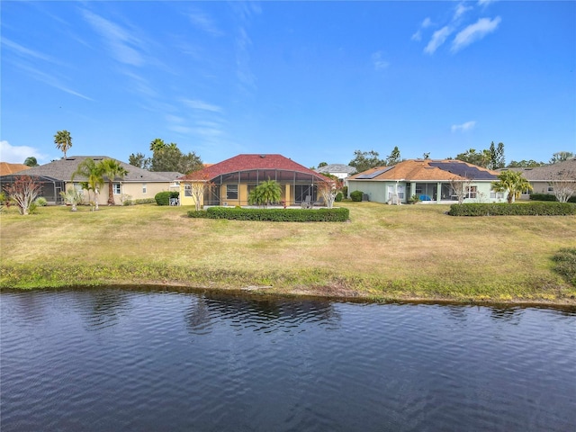 back of house with a lanai, a water view, and a lawn