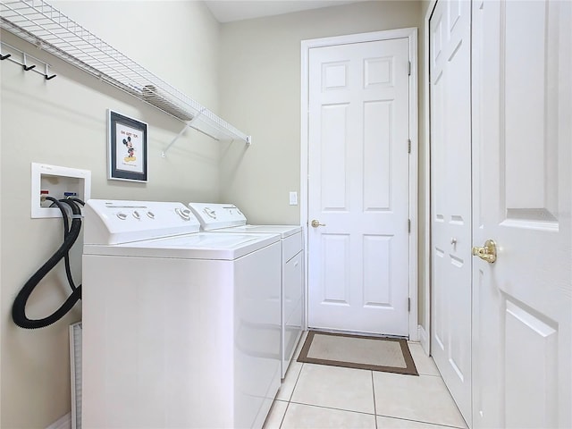 laundry area with independent washer and dryer and light tile patterned flooring