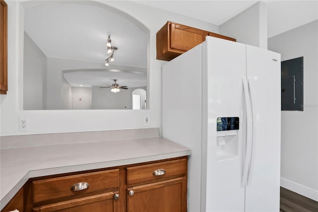 kitchen featuring electric panel, ceiling fan, white fridge with ice dispenser, and dark wood-type flooring