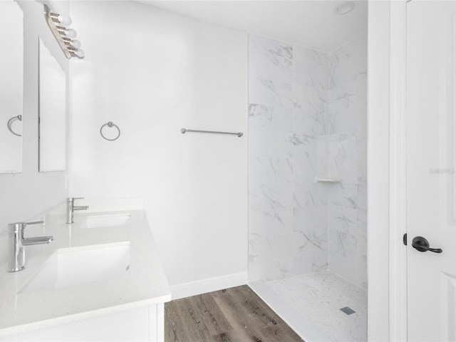 bathroom featuring vanity, wood-type flooring, and tiled shower