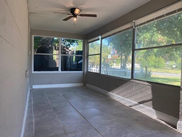 unfurnished sunroom featuring a healthy amount of sunlight and ceiling fan