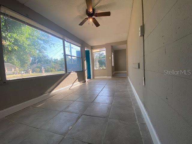 unfurnished sunroom featuring a ceiling fan