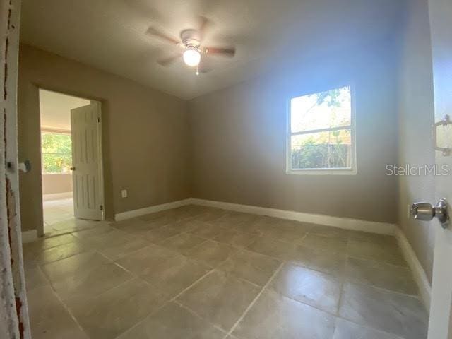 spare room with ceiling fan and baseboards