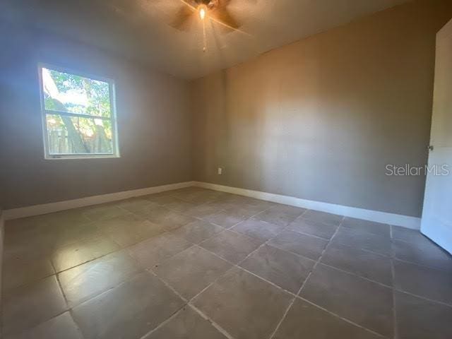 spare room with baseboards and a ceiling fan