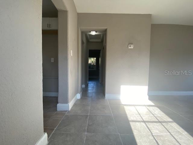 corridor featuring baseboards and tile patterned floors