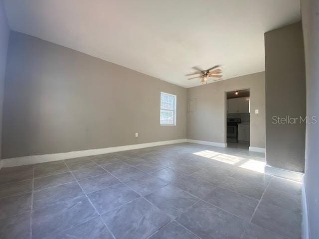 spare room featuring ceiling fan and baseboards