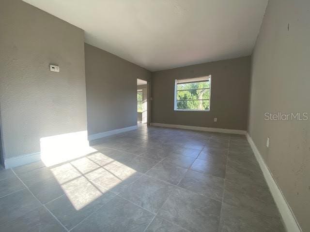 tiled spare room with lofted ceiling and baseboards