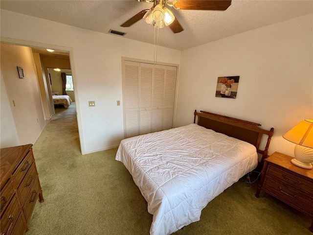 carpeted bedroom with a textured ceiling, a closet, and ceiling fan