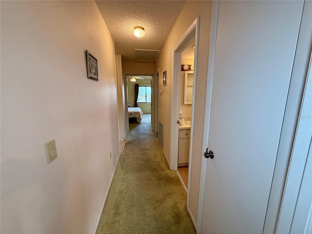 hall featuring a textured ceiling and light colored carpet