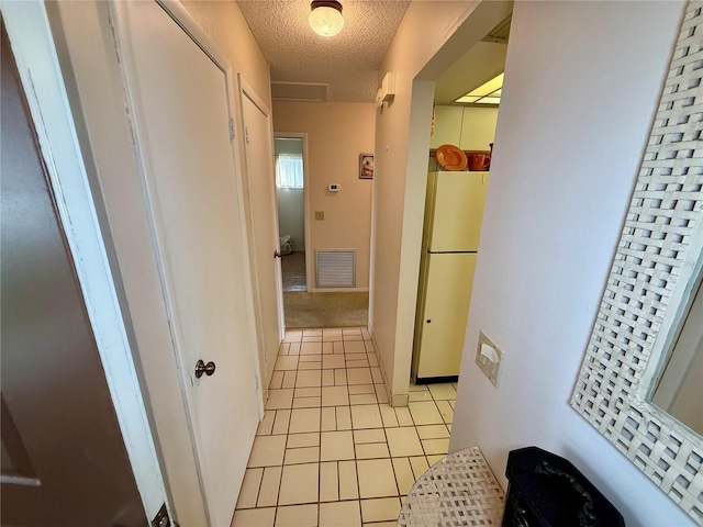 hall with light tile patterned flooring and a textured ceiling