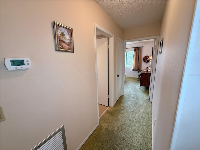 corridor with light carpet and a textured ceiling