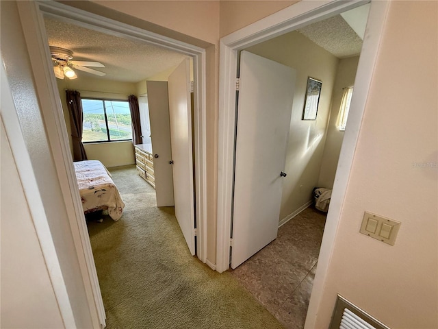 hall featuring a textured ceiling and light carpet