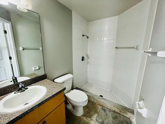 bathroom with vanity, toilet, and tiled shower