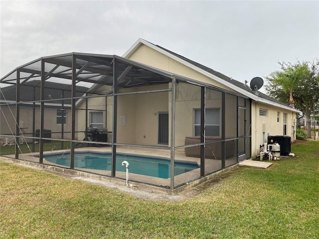 rear view of property featuring a patio area, central AC unit, glass enclosure, and a lawn