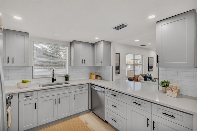 kitchen featuring backsplash, gray cabinetry, dishwasher, and sink