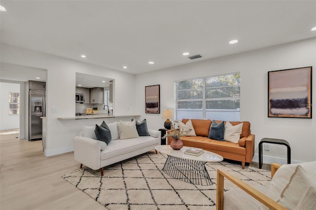 living room with light hardwood / wood-style flooring and sink