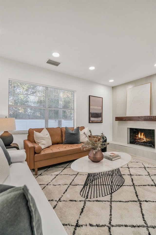 living room featuring a wealth of natural light and a tiled fireplace