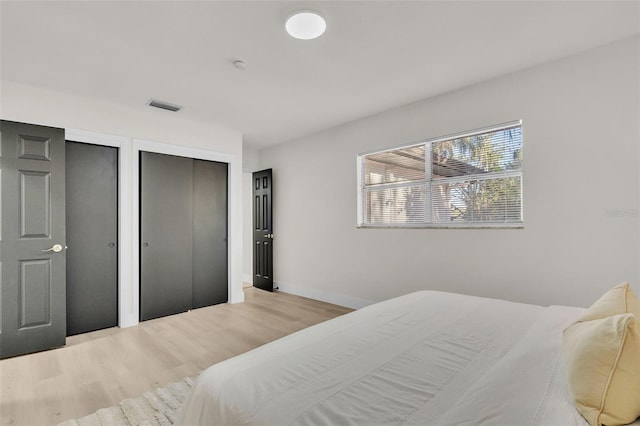 bedroom with light hardwood / wood-style floors and two closets