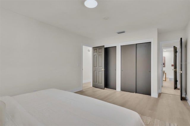 bedroom featuring light wood-type flooring and two closets