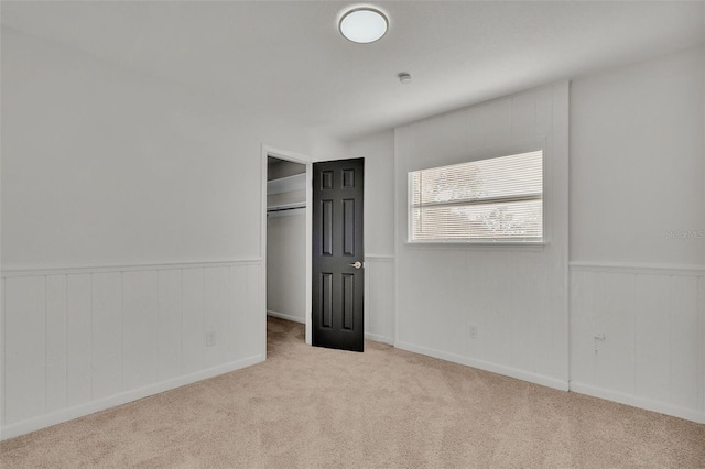 unfurnished bedroom featuring light carpet and a closet