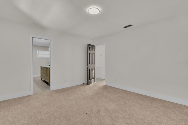 unfurnished bedroom featuring light carpet and connected bathroom