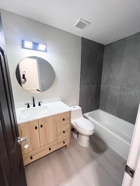 full bathroom with wood-type flooring, vanity, bathing tub / shower combination, and toilet