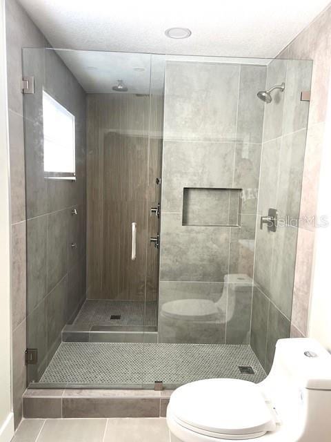 bathroom with tile patterned floors, toilet, and walk in shower