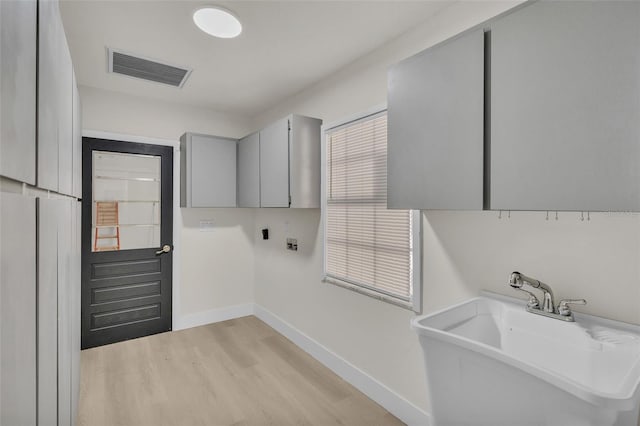 laundry area featuring cabinets, sink, hookup for a washing machine, and light hardwood / wood-style flooring