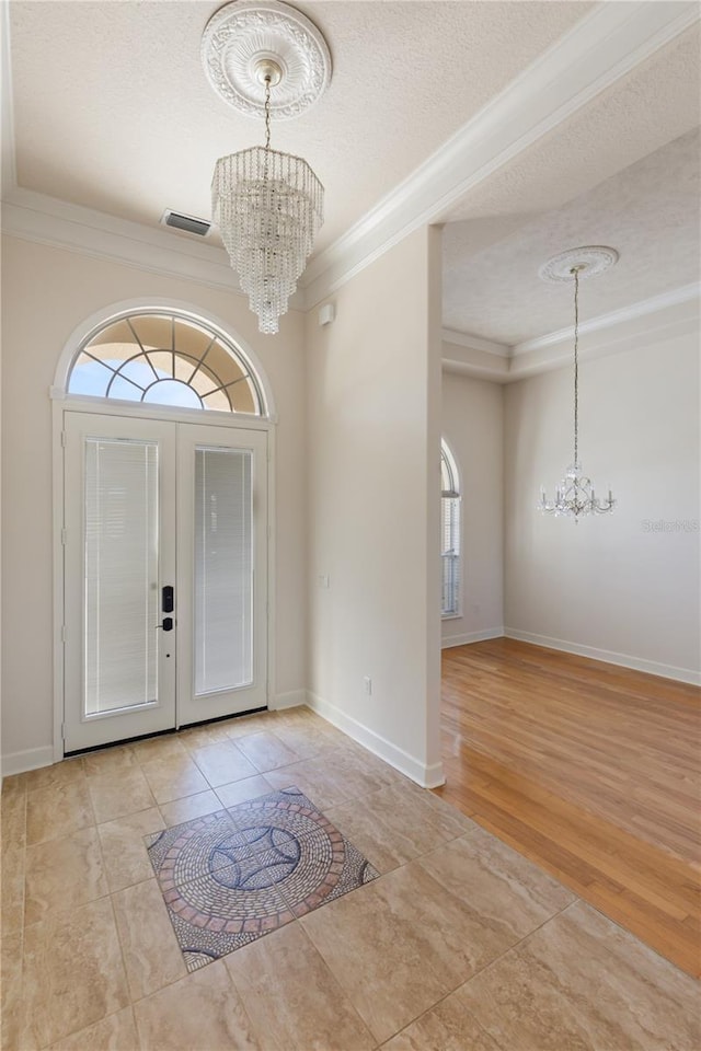 foyer featuring a textured ceiling, a wealth of natural light, and ornamental molding