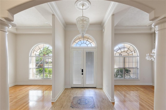 entryway featuring crown molding, light hardwood / wood-style flooring, a chandelier, and french doors