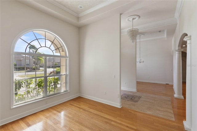 unfurnished room featuring a raised ceiling, plenty of natural light, and a notable chandelier