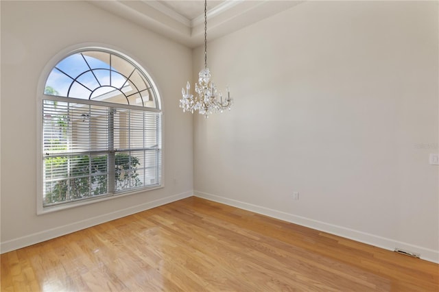 unfurnished room with light wood-type flooring, crown molding, and a chandelier