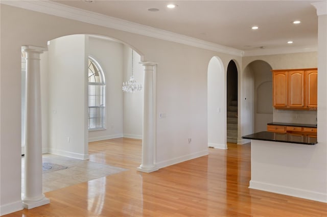 interior space featuring light wood-type flooring, ornamental molding, and a notable chandelier